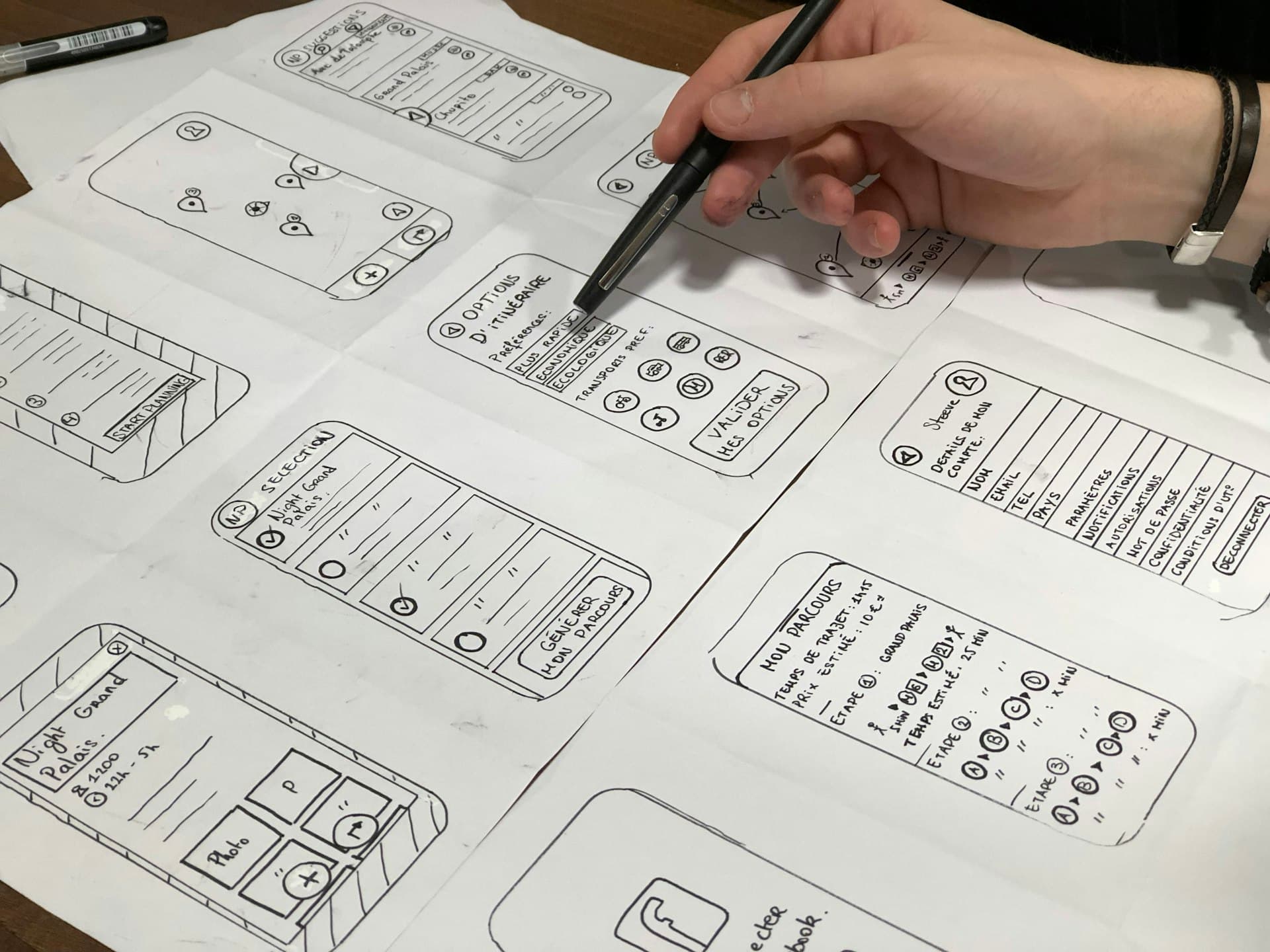 Mão desenhando esboços de telas de aplicativo em papel