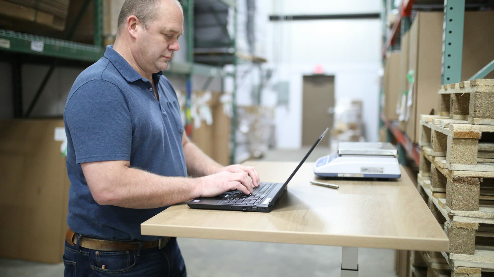 Gestor usando um notebook numa mesa de apoio dentro de um depósito